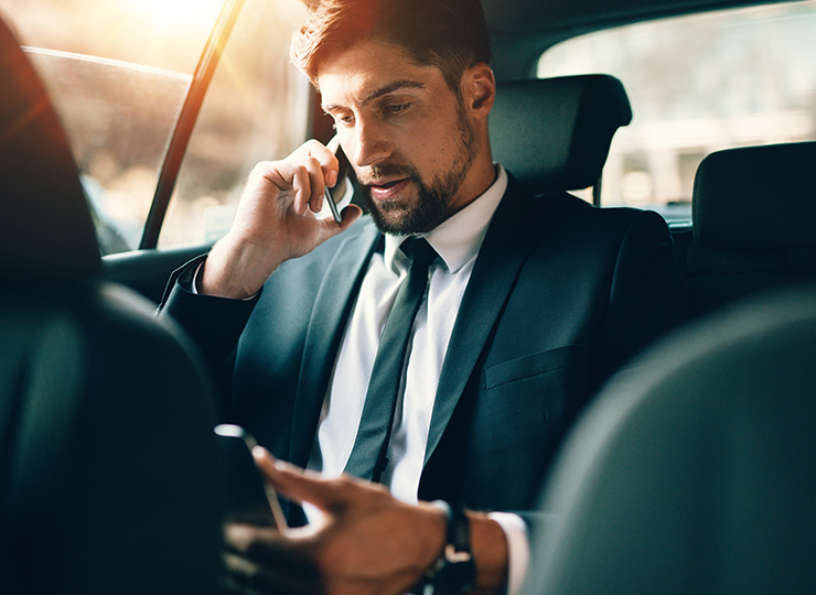 A corporate traveller talking on his phone within a car